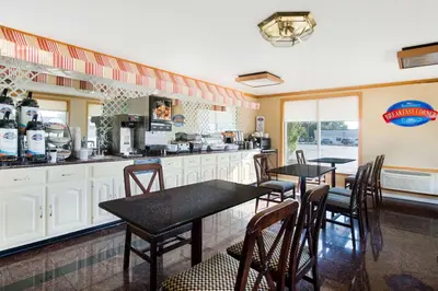 a kitchen with two tables and chairs and a counter at Baymont by Wyndham Sandusky in Sandusky