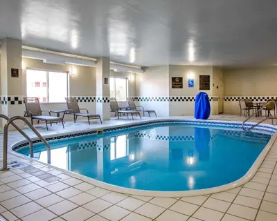 a pool in a hotel room with chairs and tables at Comfort Suites Columbus West - Hilliard in Columbus