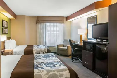 a hotel room with two beds and a flat screen tv at Sleep Inn & Suites Oregon - Toledo in Oregon