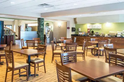 a restaurant with wooden tables and chairs and a counter at Sleep Inn & Suites Oregon - Toledo in Oregon