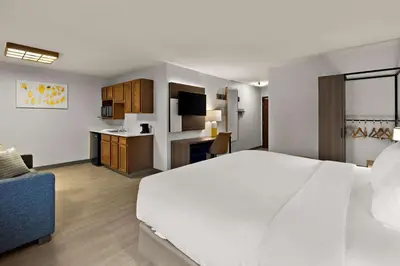 a hotel room with a large white bed and a kitchen at Comfort Inn & Suites Fremont in Fremont