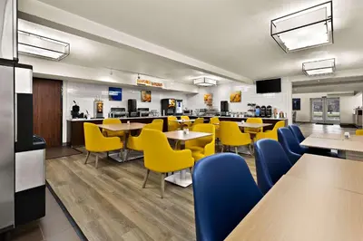 a restaurant with yellow chairs and tables and a cafeteria at Comfort Inn & Suites Fremont in Fremont