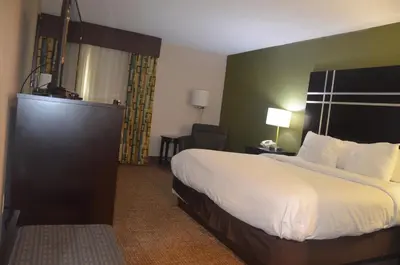 a hotel room with a large bed and a chair at Comfort Inn & Suites Maumee - Toledo I80-90 in Maumee