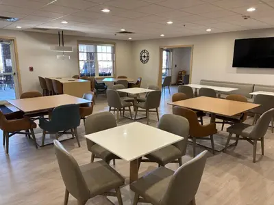 a waiting room with tables and chairs and a flat screen tv at Comfort Suites Hotel and Conference Center in Berlin