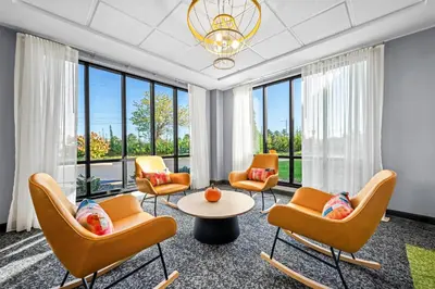 a waiting room with chairs and a table and windows at Spark By Hilton Cleveland Beachwood in Beachwood