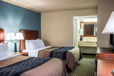 a hotel room with two beds and a mirror at Days Inn by Wyndham Austintown in Austintown