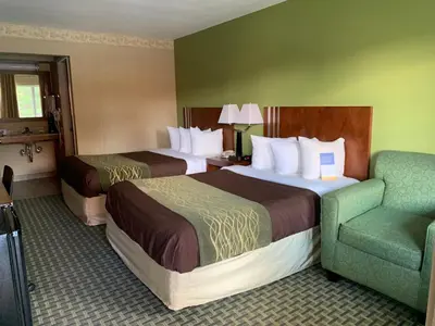 a hotel room with two beds and a chair at Days Inn by Wyndham Austintown in Austintown