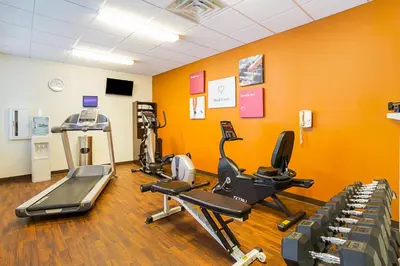 a gym with cardio equipment in a room with orange walls at Comfort Suites Twinsburg in Twinsburg