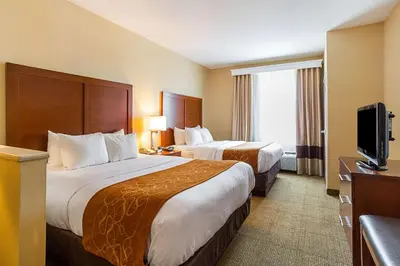 a hotel room with two beds and a flat screen tv at Comfort Suites Twinsburg in Twinsburg