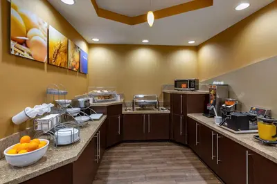 a large kitchen with brown cabinets and oranges on the counter at Comfort Suites Perrysburg - Toledo South in Perrysburg