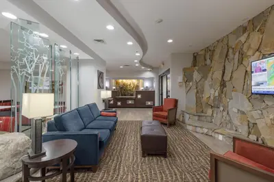a lobby with a blue couch and a stone wall at Comfort Suites Perrysburg - Toledo South in Perrysburg