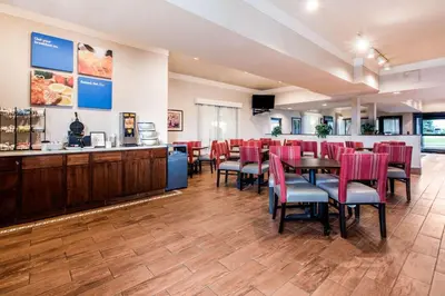 a dining room with red chairs and a bar at Comfort Inn & Suites Streetsboro - Kent in Streetsboro