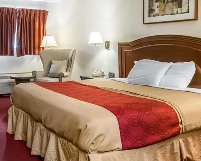 a hotel room with a large bed and a chair at Econo Lodge Holland - Toledo in Holland