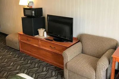 a hotel room with a tv and a chair and a dresser at Quality Inn Holland - Toledo in Holland