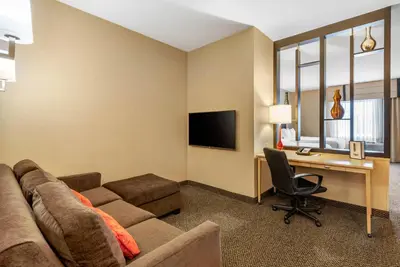 a living room with a couch and a desk with a computer at Cambria Hotel Akron - Canton Airport in Uniontown