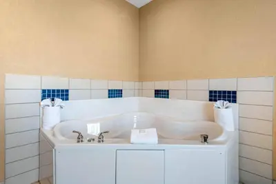 a white tub in a bathroom with blue and white tiles at Cambria Hotel Akron - Canton Airport in Uniontown