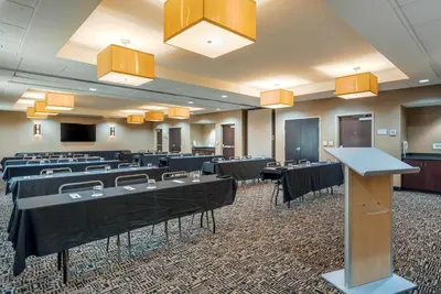 a conference room with tables and chairs and a podium at Cambria Hotel Akron - Canton Airport in Uniontown