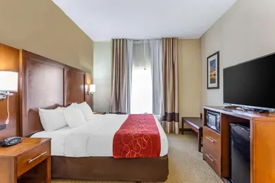 a hotel room with a bed and a flat screen tv at Comfort Suites South Point - Huntington in Burlington