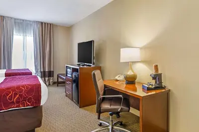 a hotel room with a bed and a desk with a computer at Comfort Suites South Point - Huntington in Burlington