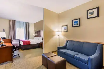 a hotel room with a couch and a bed at Comfort Suites South Point - Huntington in Burlington