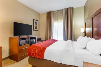 a hotel room with a bed and a flat screen tv at Comfort Suites South Point - Huntington in Burlington