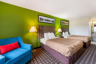 a hotel room with two beds and a blue chair at Quality Inn - Huron, Sandusky OH in Huron
