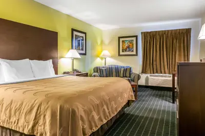 a hotel room with a bed and a chair at Quality Inn Jackson in Jackson