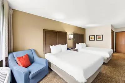 a hotel room with two beds and a blue chair at Comfort Inn Van Wert in Van Wert