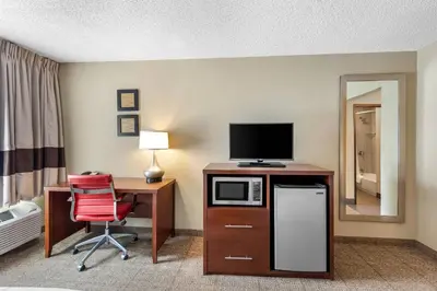a room with a desk with a microwave and a television at Comfort Inn Mayfield Heights Cleveland East in Mayfield