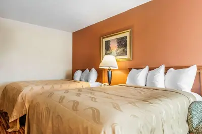 two beds in a hotel room with orange walls at Quality Inn Gallipolis in Gallipolis