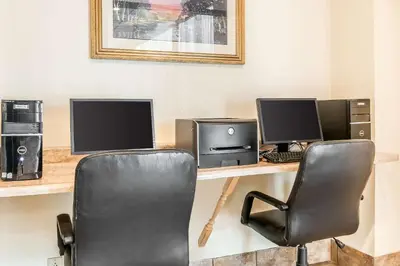 a desk with three computer monitors and a chair at Quality Inn Gallipolis in Gallipolis
