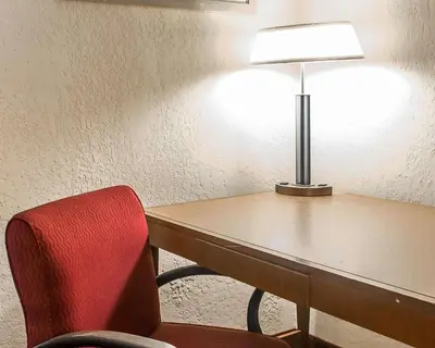 a room with a desk with a red chair and a lamp at Economy Inn & Suites in Warren
