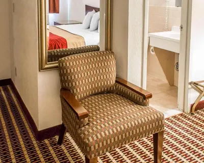a chair in a room with a mirror and a bed at Economy Inn & Suites in Warren