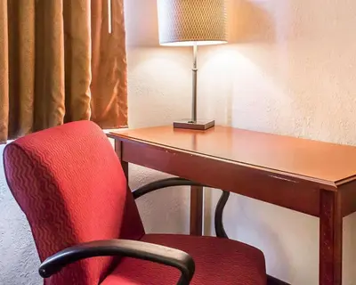 a desk with a red chair next to a table with a lamp at Economy Inn & Suites in Warren