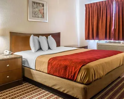 a hotel room with a bed with a red window at Economy Inn & Suites in Warren