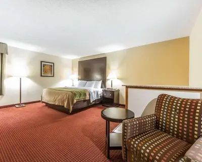 a hotel room with a bed and a chair at Quality Inn & Suites Portsmouth in Rosemount