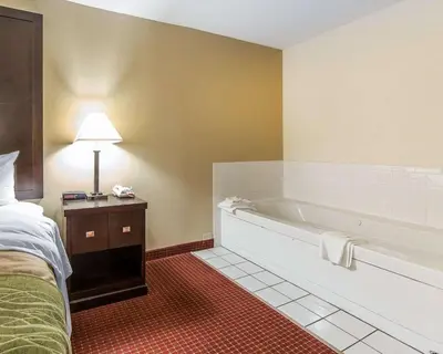 a hotel room with a tub and a bed at Quality Inn & Suites Portsmouth in Rosemount