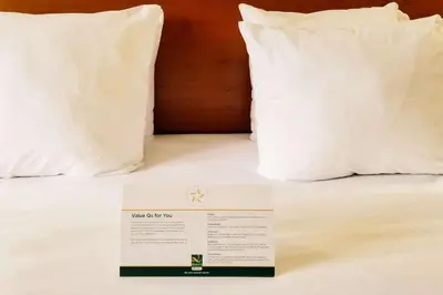 a hotel room with two pillows and a sign on a bed at Quality Inn & Suites Cincinnati Sharonville in Sharonville