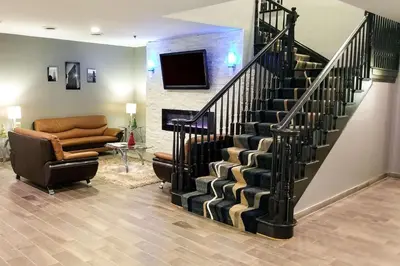 a lobby with a staircase with a couch and a chair at Quality Inn & Suites Cincinnati Sharonville in Sharonville