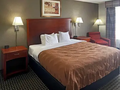 a hotel room with a large bed and a chair at Quality Inn & Suites Cincinnati Sharonville in Sharonville