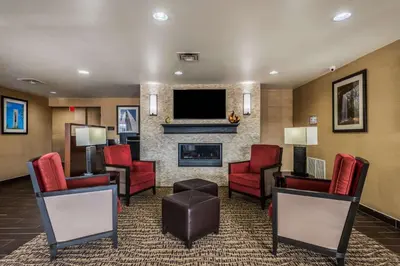 a lobby with chairs and a fireplace and a tv at Comfort Inn & Suites Dayton North in Dayton