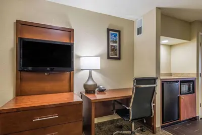 a hotel room with a desk with a television and a chair at Comfort Inn & Suites Dayton North in Dayton