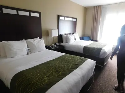 a hotel room with two beds and a person standing between them at Comfort Inn St Clairsville in Saint Clairsville
