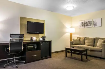 a hotel room with a couch and a flat screen tv at Sleep Inn & Suites Pittsburgh Airport in Imperial