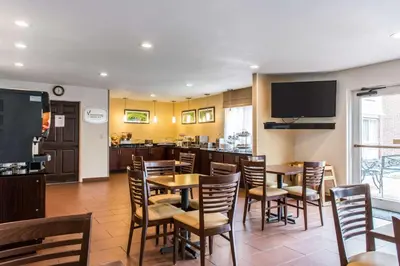 a dining room with tables and chairs and a television at Sleep Inn & Suites Pittsburgh Airport in Imperial