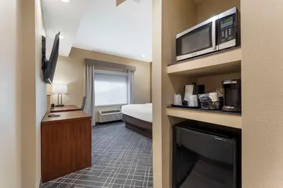a small hotel room with a bed and a microwave at Comfort Suites Monaca in Monaca