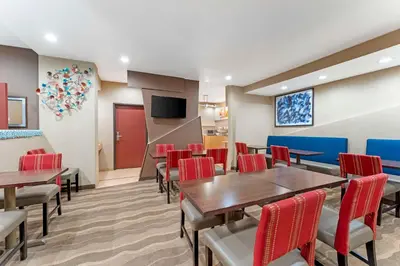 a dining room with tables and chairs and a tv at Comfort Suites Monaca in Monaca