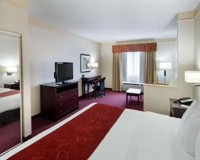 a hotel room with a bed and a desk with a television at Comfort Suites Parkersburg South in Mineralwells