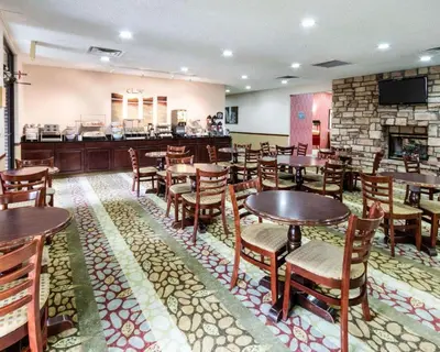 a restaurant with tables and chairs and a fireplace at Comfort Suites Parkersburg South in Mineralwells