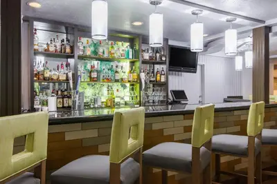 a bar with four chairs and a counter with drinks at Wyndham Garden Hotel Cross Lanes Charleston in Charleston